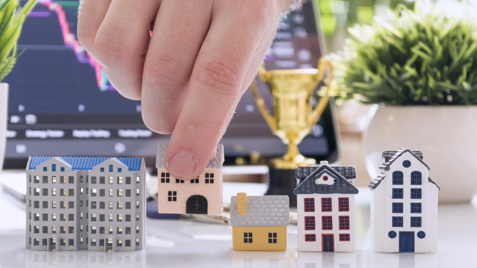 Hand placing a miniature house among model homes representing real estate investment opportunities under the India–UK Free Trade Agreement