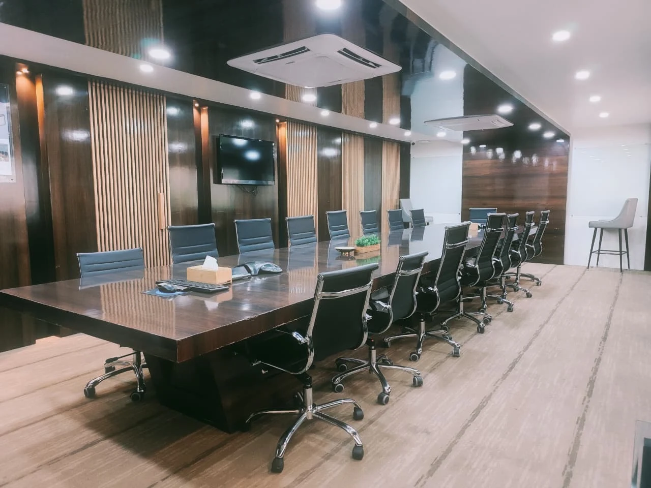 Modern conference room at King Stubb & Kasiva’s Bangalore office with a large wooden meeting table, black office chairs, and wall-mounted TV.