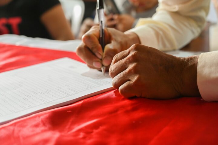 a person writing on a piece of paper - Margin Pledge And Invocation Process