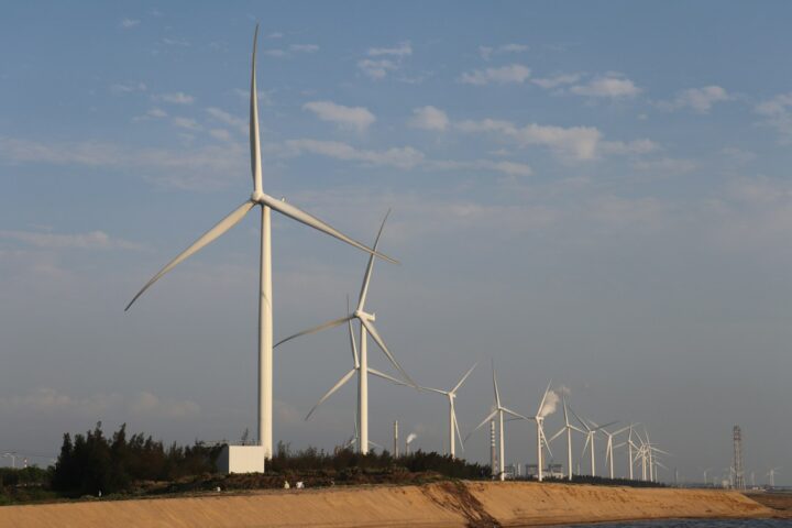 a row of wind turbines next to a body of water