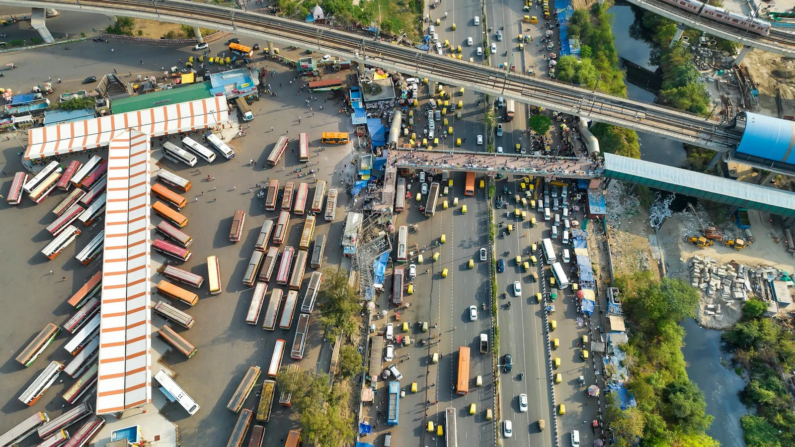 cross-border infrastructure financing india fema ecb - Aerial view of a busy bus station and roadway with vibrant urban activ