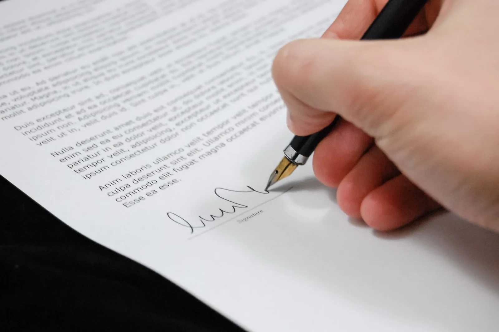 free consent indian contract act - - Close-up of a hand signing a legal document with a fountain pen, symbolizing signature a
