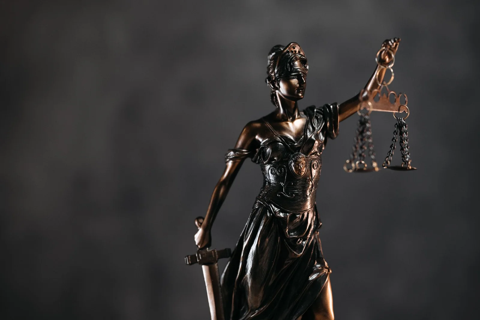 finality of arbitral awards judicial intervention - Detailed bronze Lady Justice statue with scales and sword against a dark