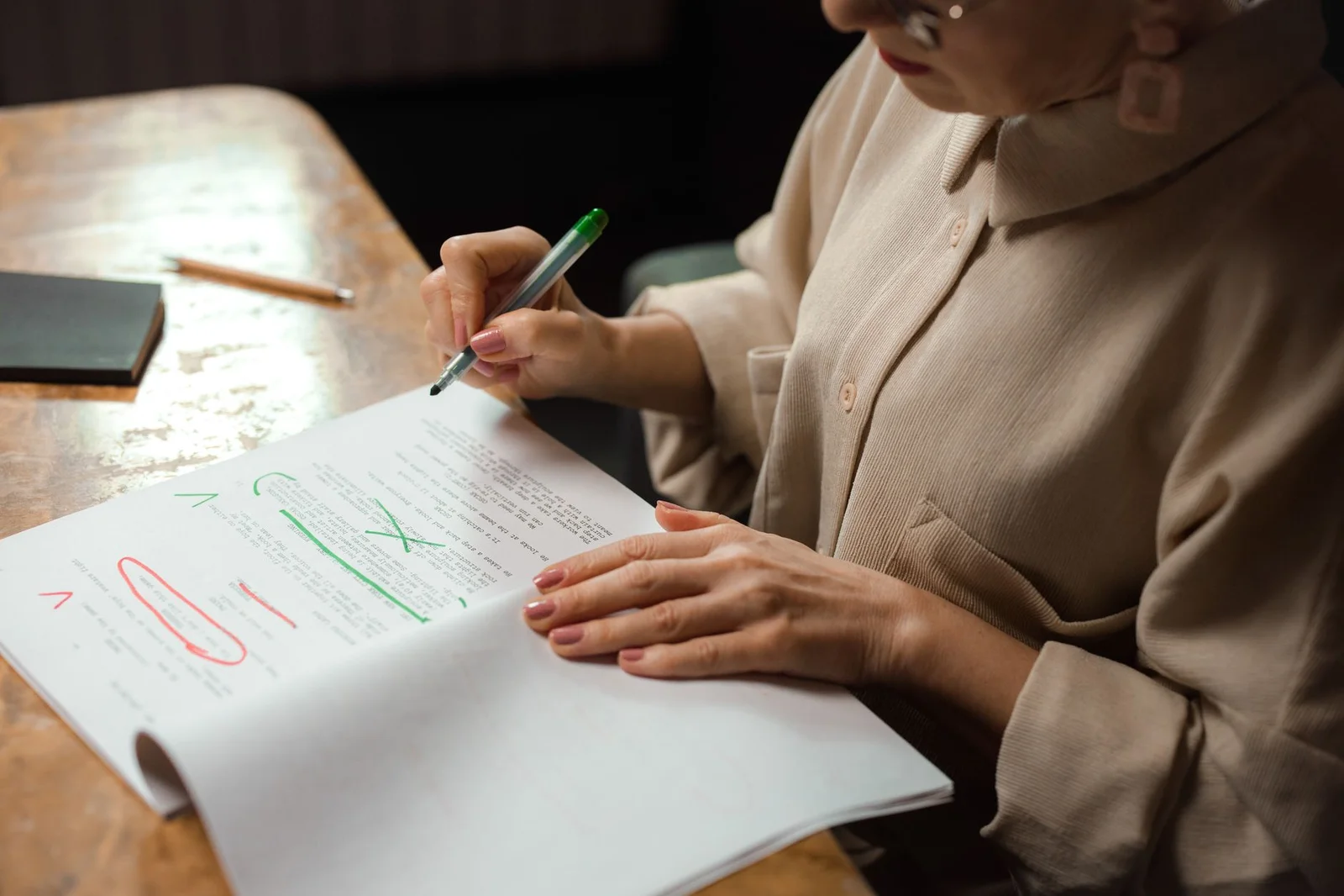 post-award corrections section 33 arbitration act - Close-up of a senior woman editing a manuscript at a desk with a green ma