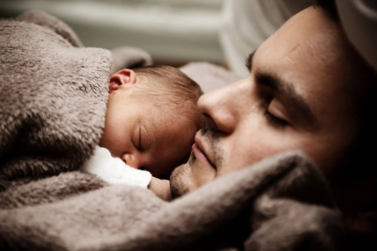 paternity leave framework india - Towards - A touching close-up of a father and his baby peacefully napping together.