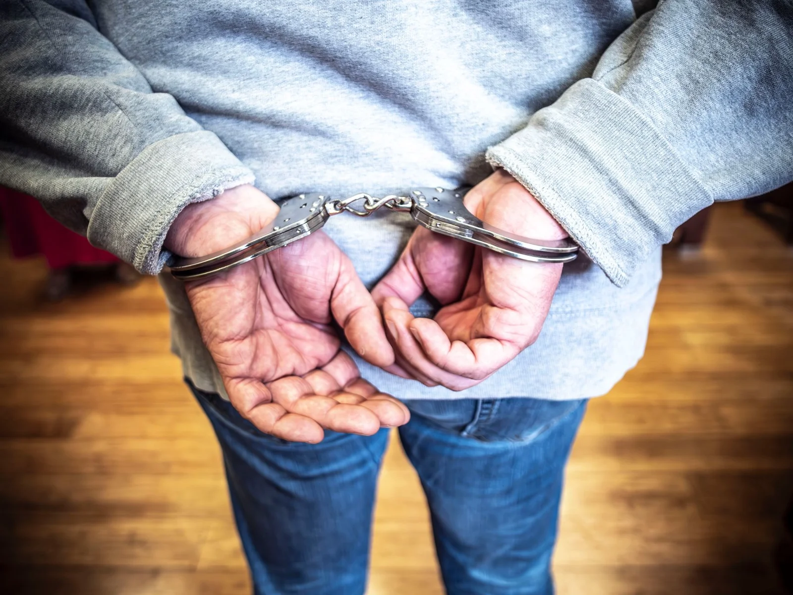 arrest private complaint non-bailable warrant magistrate - Close-up of a person in handcuffs viewed from behind, wearing casu