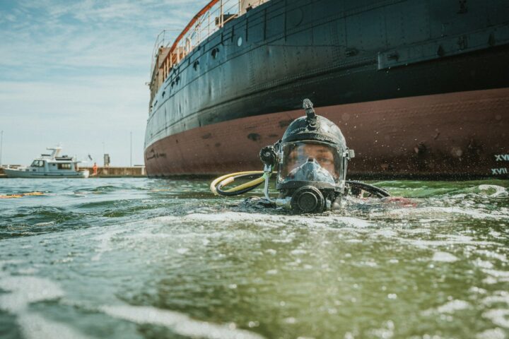 A diver surfaces near a large ship. - maritime environmental liability