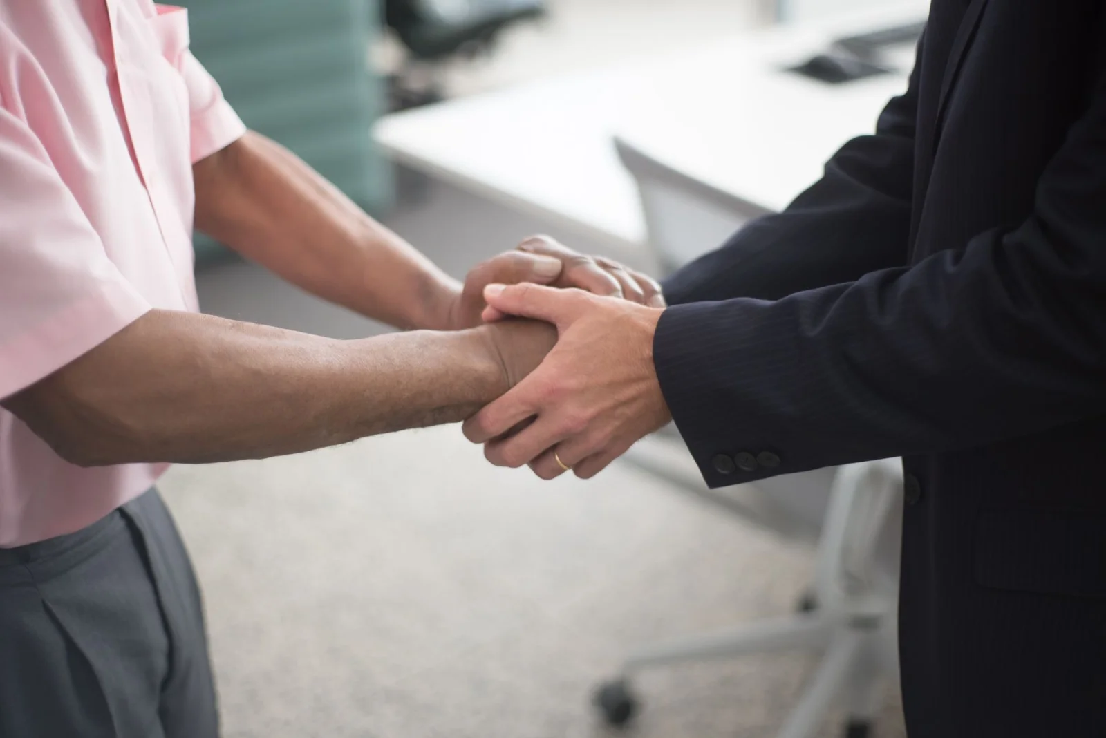 What Happens to ESOPs During an - Close-up of a formal handshake between two businessmen in an office environment.